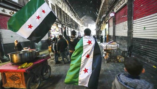 Anhänger der Opposition tragen am Dienstag, dem 10. Dezember 2024, auf dem Al-Hamidiyeh-Markt in der von einer Stadtmauer umgebenen Altstadt von Damaskus, Syrien, Fahnen der Opposition.(Foto: picture alliance / AP| Hussein Malla)