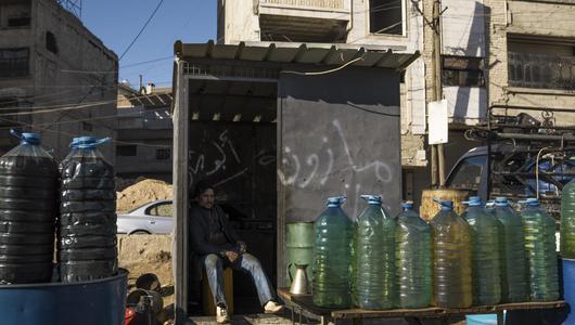 Ein Mann verkauft auf der Straße in Syrien Treibstoff aus Plastikflaschen.