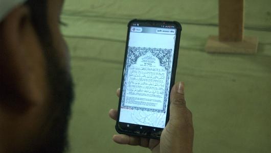 A man reads the Qur'an on a smartphone.