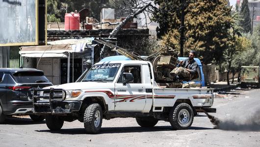 Ein Pickup-Wagen mit aufgesetzter Waffe, dahinter ein Mann.