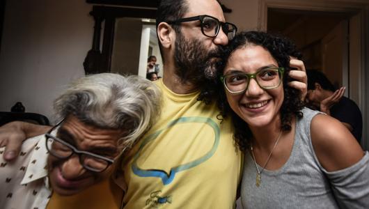 Ein Mann und zwei Frauen umarmen und freuen sich