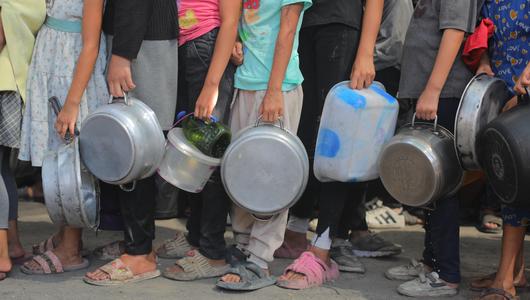 أطفال يحملون الطناجر والصحون ويقفون في طابور 