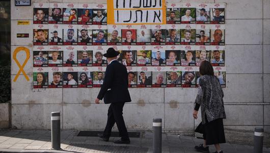 Eine Frau und ein Mann schauen auf die Fotos der Geiseln in Jerusalem