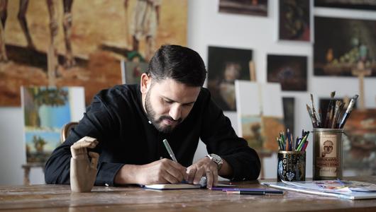 A man sits at a desk writing in a notepad.