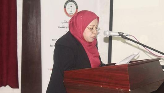 Eine Frau mit Hidschab und Brille spricht auf einem Podium.