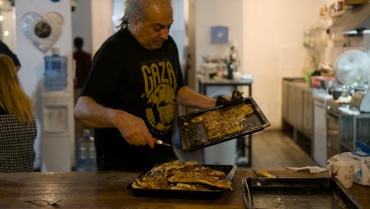 A man is distributing food in a kitchen.