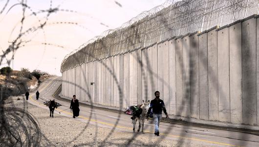 Palestinian farmers walk next to the Israeli separation barrier after the Israeli army allowed them to cross from the West Bank village of Beit Awwa to harvest olives on their land near the Israeli community of Shekef, Wednesday, Oct. 26, 2022.