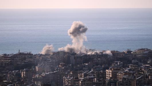 Eine Rauchwolke steigt aus einem Gebäude in einem dicht bebauten Stadtteil von Beirut auf. Im Hintergrund sind das Meer und der Himmel zu sehen.